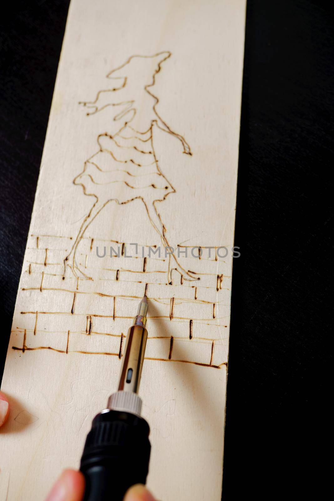 close-up of a wooden board with a pyrographed drawing on a black background