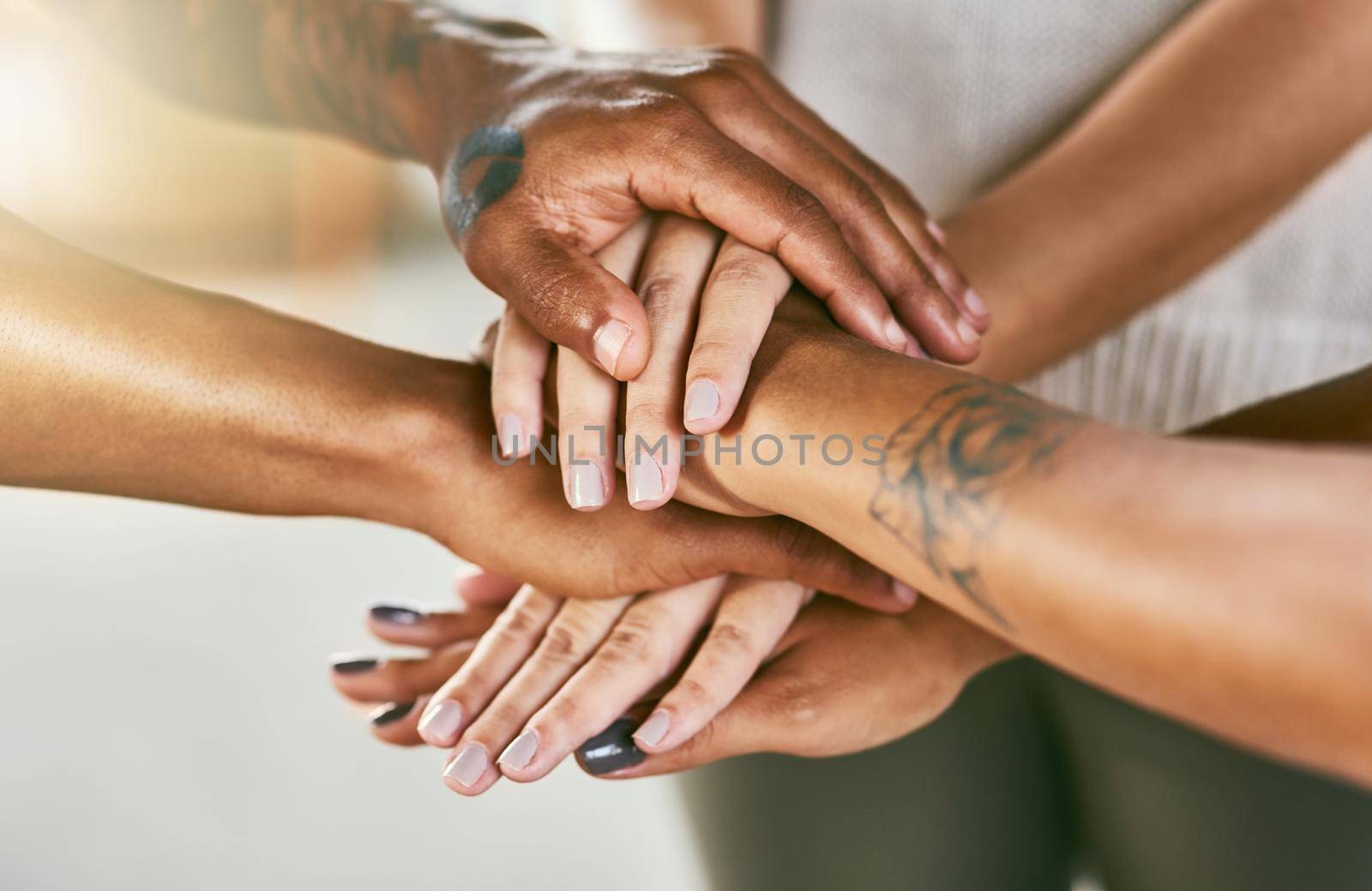 Lets work together to grow together. Closeup shot of a group of people joining their hands in a huddle. by YuriArcurs