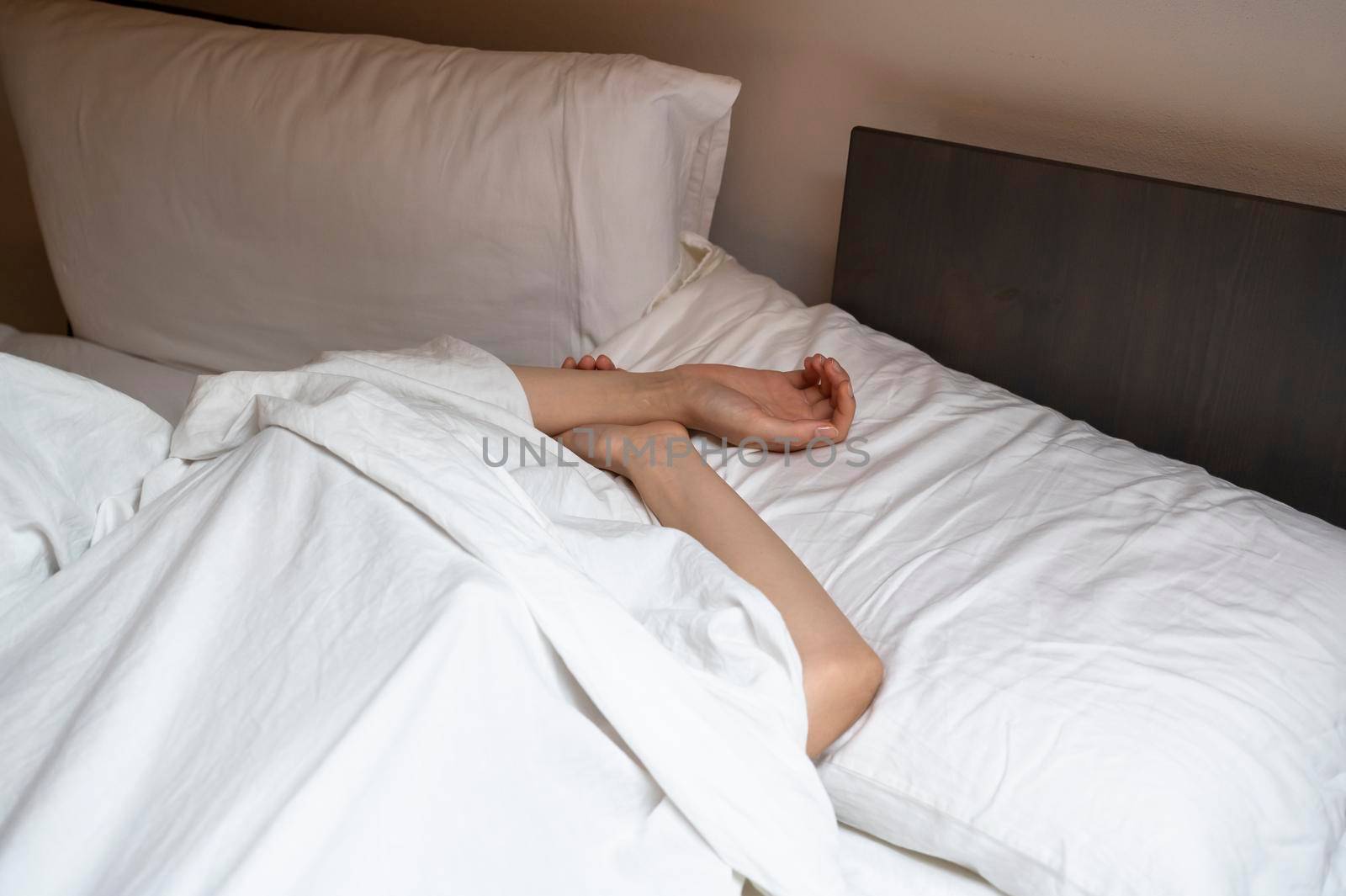 Woman sleeping in the bed under white sheet.