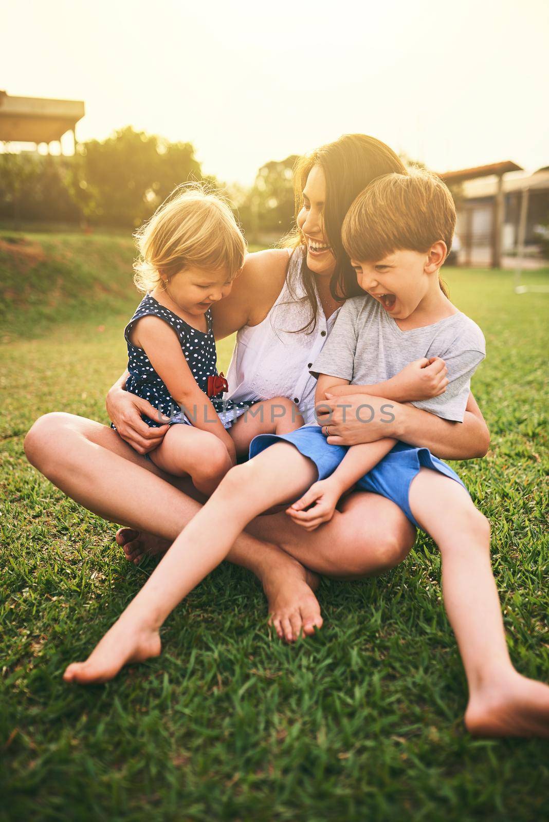 Her kids are her absolute world. a mother bonding with her two adorable little children outdoors. by YuriArcurs