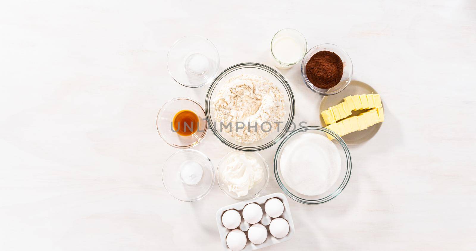 Flat lay. Ingredients in glass bowls to bake chocolate bundt cake with chocolate frosting.