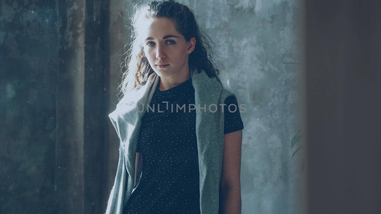 Portrait of attractive young girl standing still in and looking at camera. Dust flying around sunny room by silverkblack