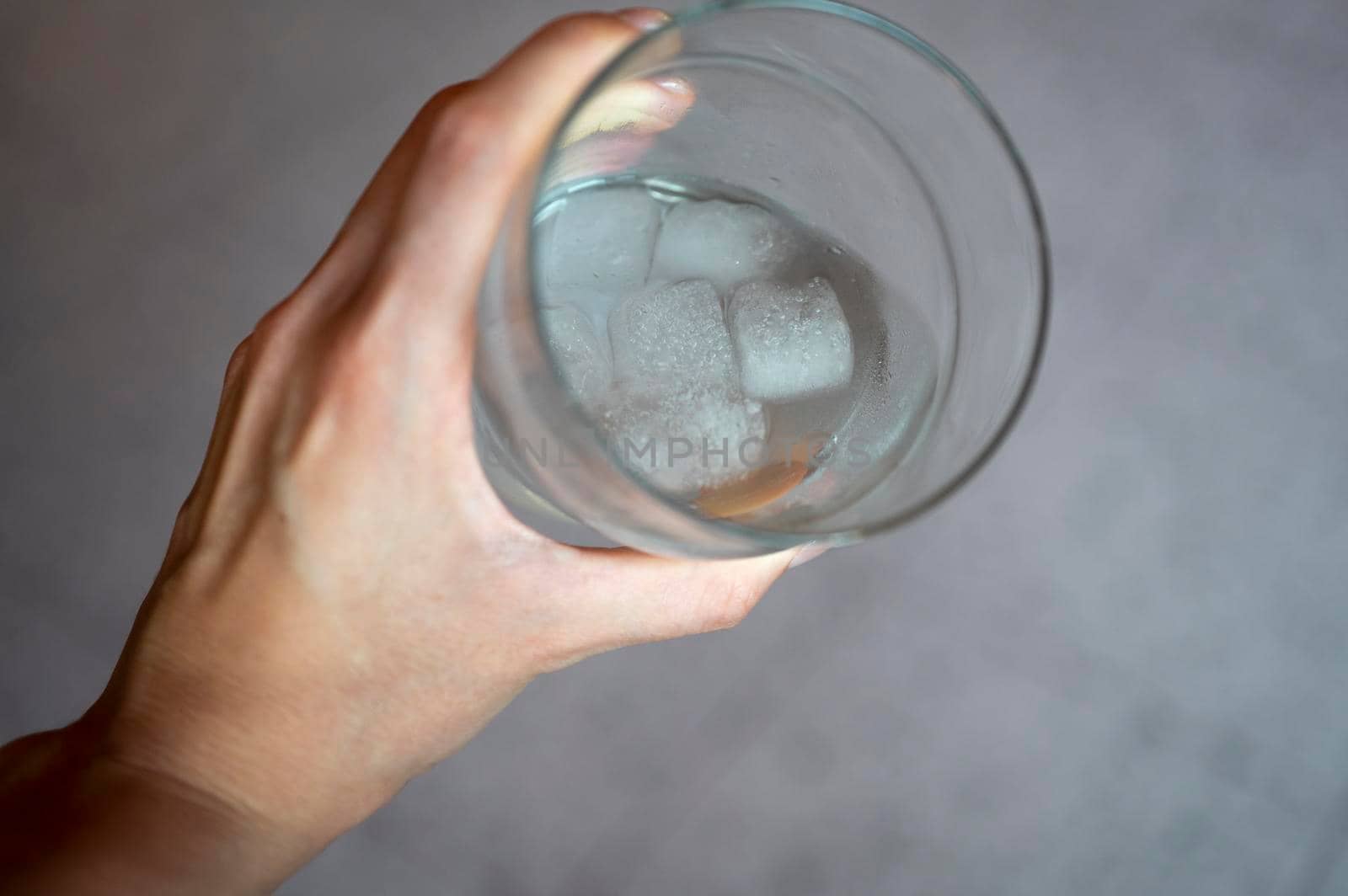 Woman hand holding a fresh glass of water with ice.