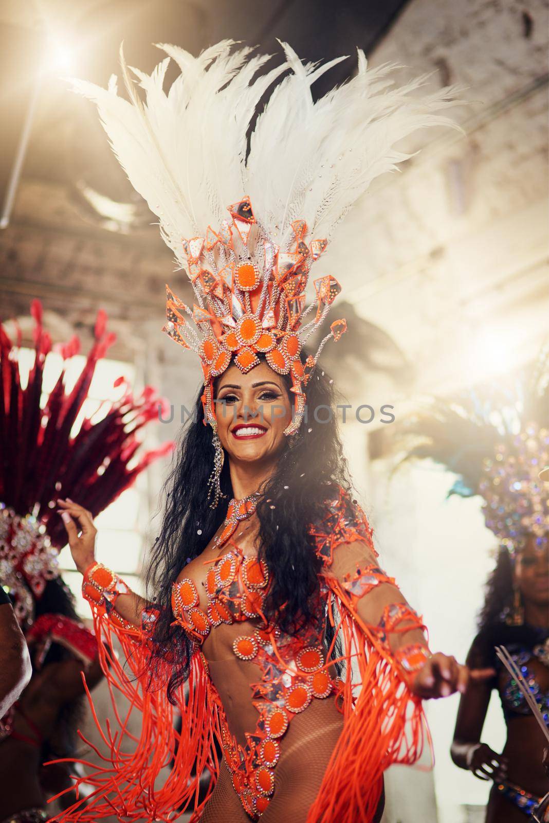 Let the festivities begin. Portrait of a cheerful female dancer wearing a vibrant costume while dancing inside a busy nightclub