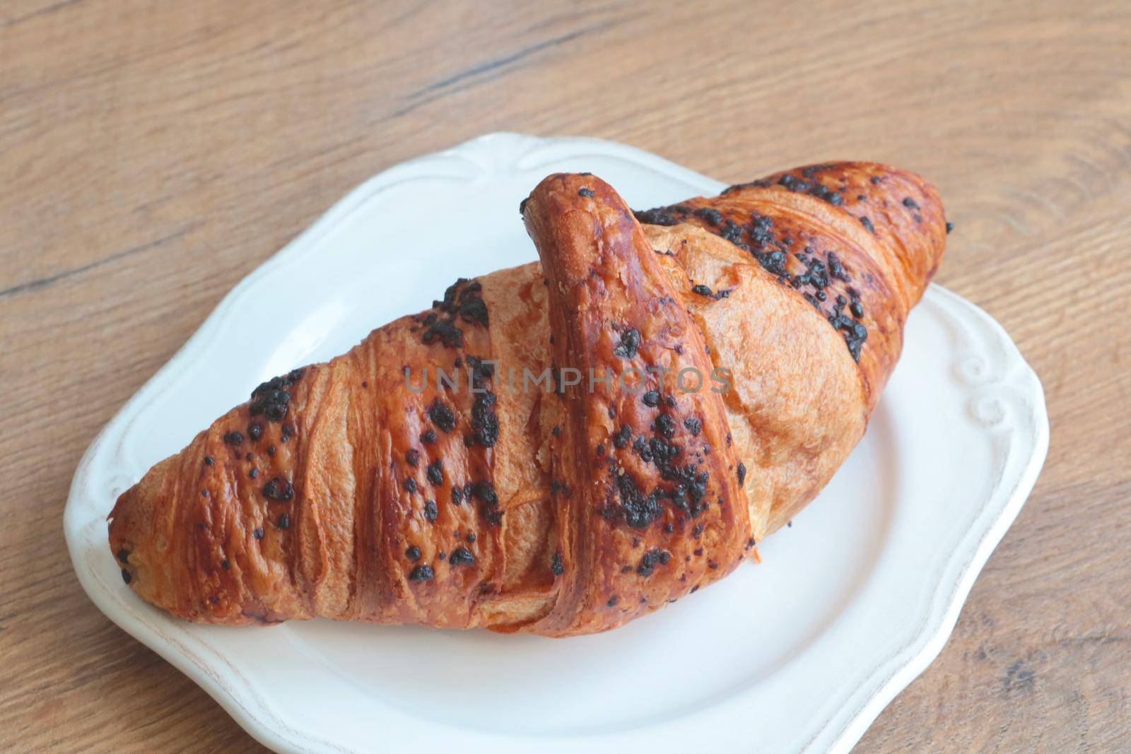 There is a delicious and fresh croissant on the plate. Fresh bakery. Sweets for tea or coffee. Bakery with fresh pastries. Food concept