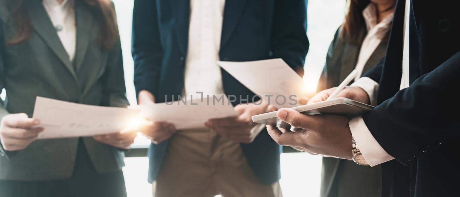 Group of young cheerful business people working together on new project while standing in the creative office by nateemee