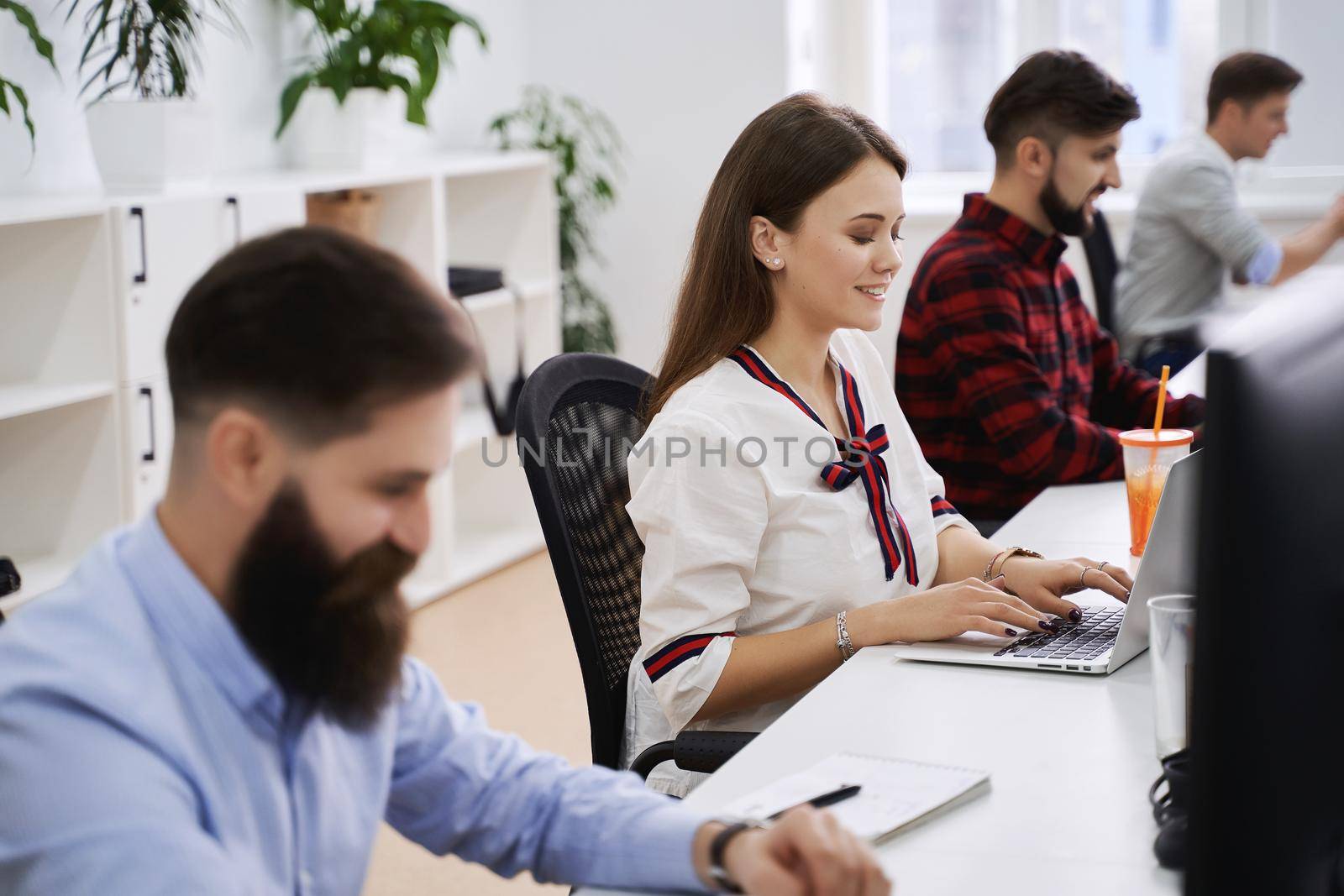 People working in modern IT office. Group of young programmers and software developers sitting at desks working on computers. Team at work.