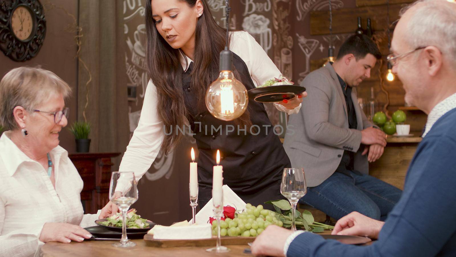 Beautiful waiter serving a beautiful senior couple in a restaurant. Romantic couple. Couple relaxing.