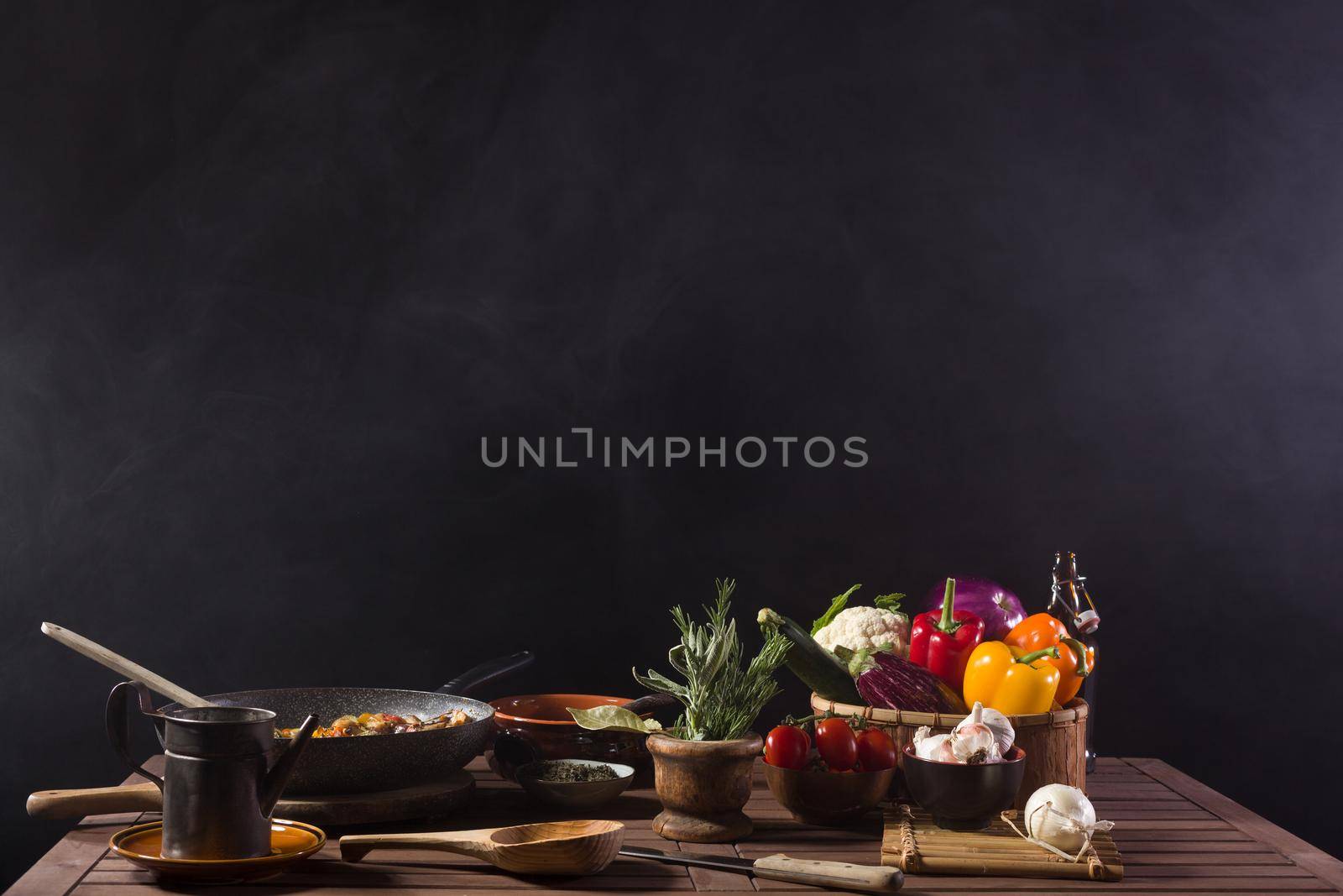 Fresh vegetables cooked in a pan still steaming on the wooden table of a restaurant kitchen. Copy space on top