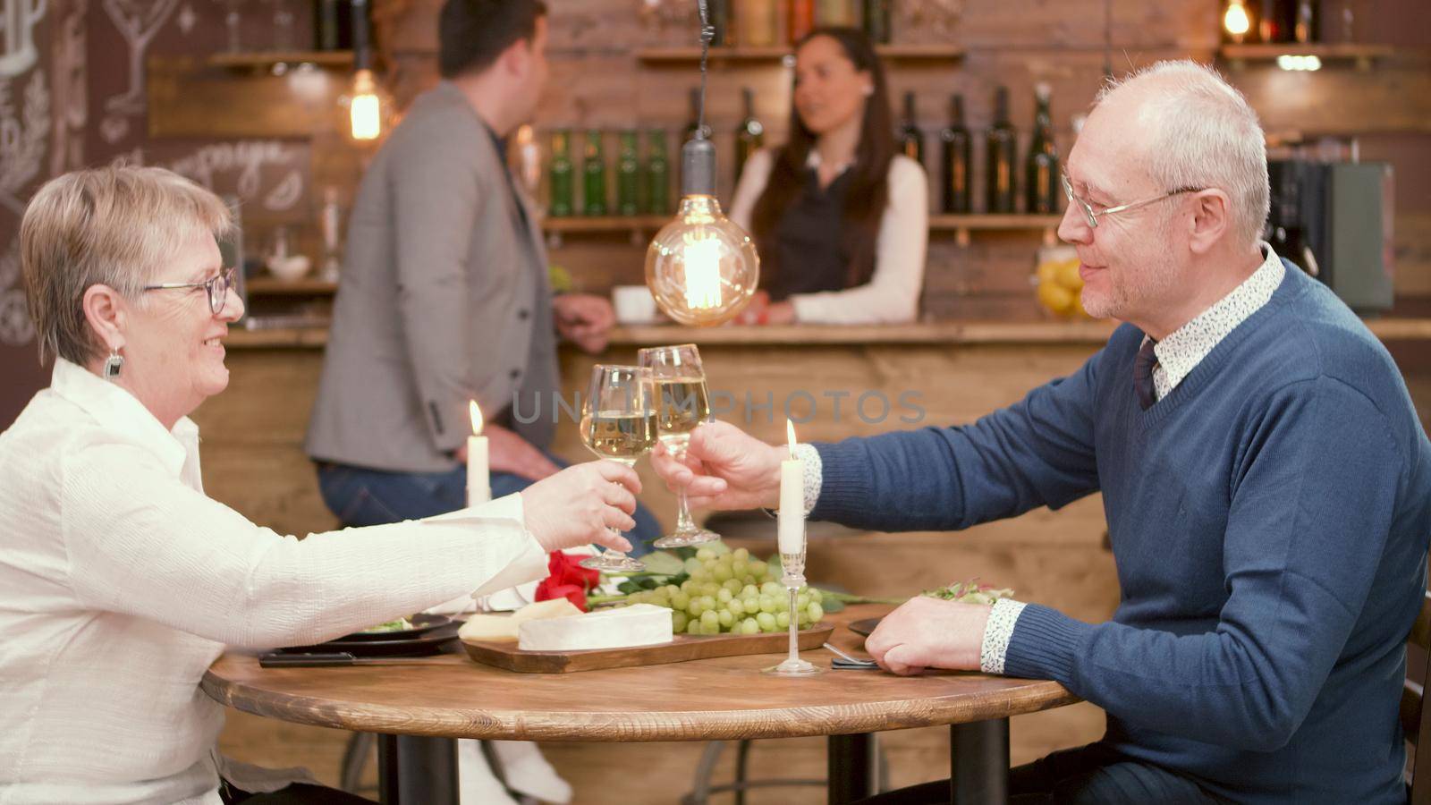 Senior man clinking glasses with his wife on their date in a restaurant. Romantic couple. Beautiful old couple.