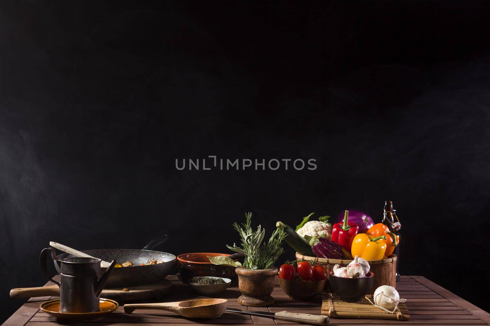 Fresh vegetables cooked in a pan still steaming on the wooden table of a restaurant kitchen. Copy space on top