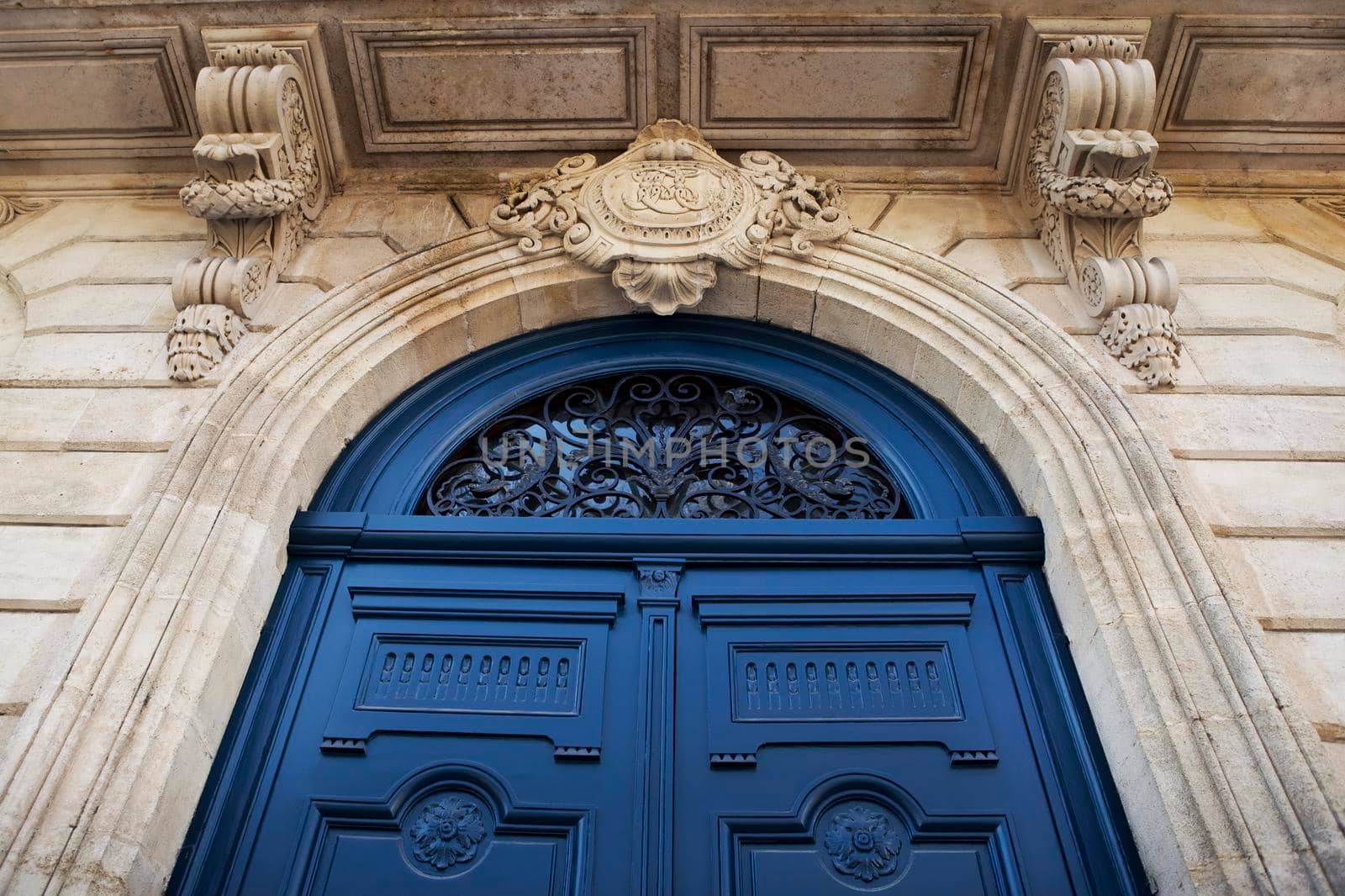Wooden blue door on the stoned facade of a French mansion