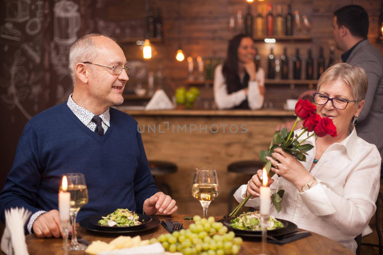 Senior man giving a bouquet of flowers to his wife. Couple in their sixties. Enjoying retirement.