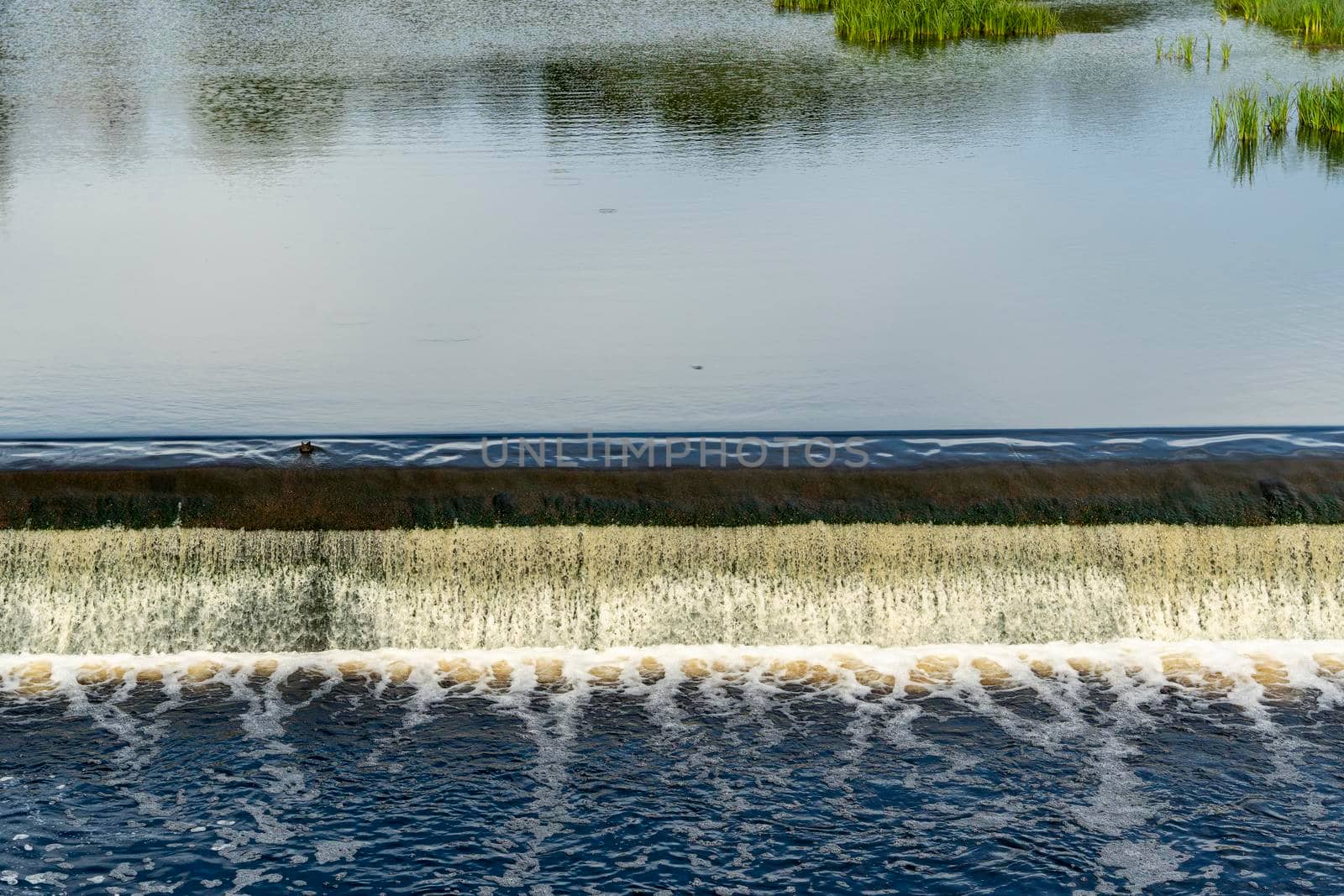 a dam on a small river. Water flows from a small river dam, boils, foams and falls down. construction engineering structure. hydroelectric