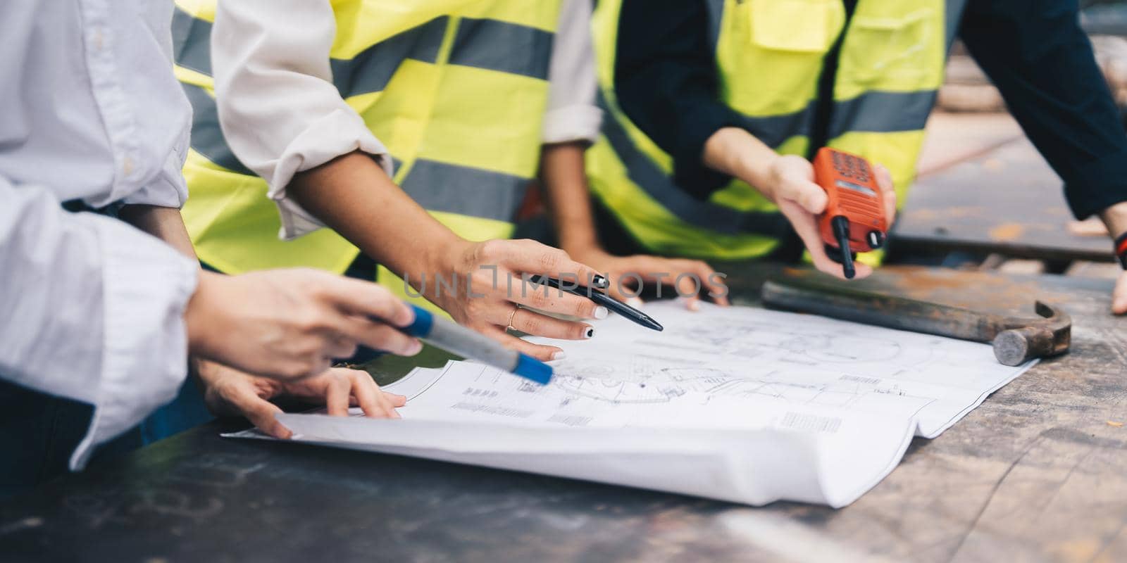 Three colleagues discussing data working with architectural project at construction site