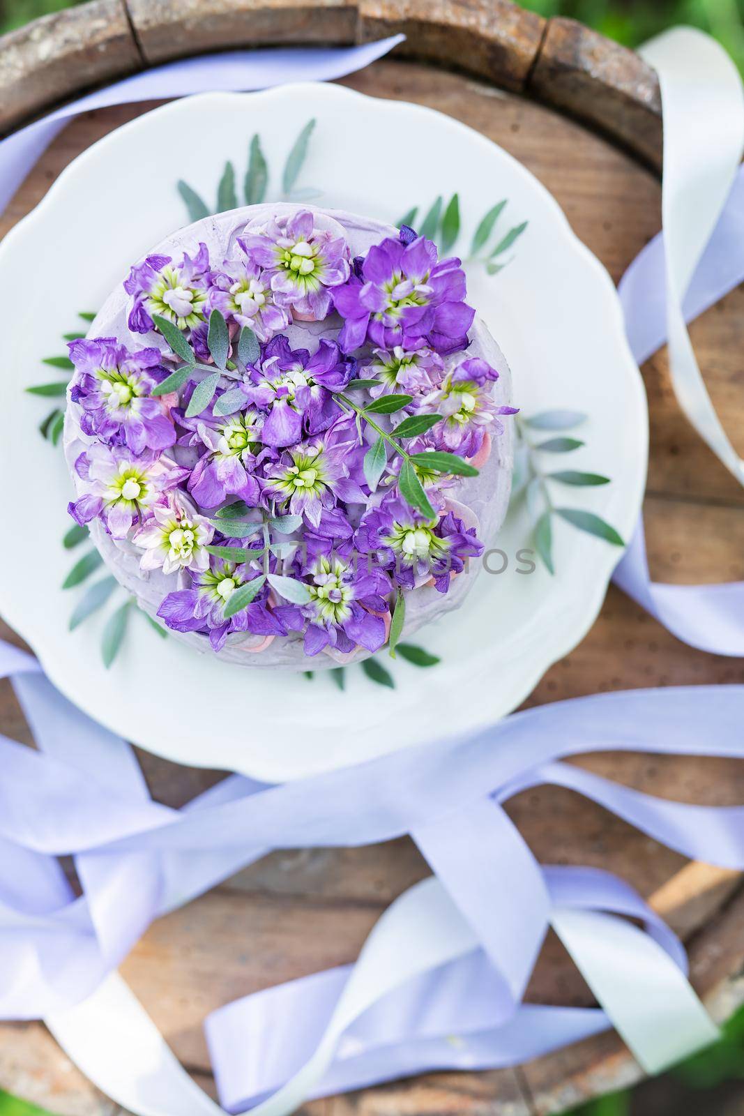 Very beautiful bento cake with purple, veri peri, matthiola flowers with green leaves, top view. Birthday, beautiful ribbons