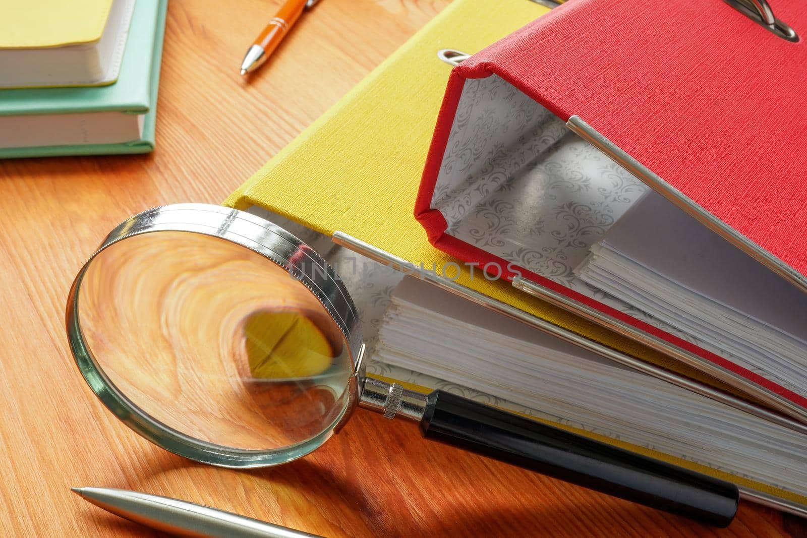 Workplace investigation concept. Two Folders with papers and a magnifying glass.