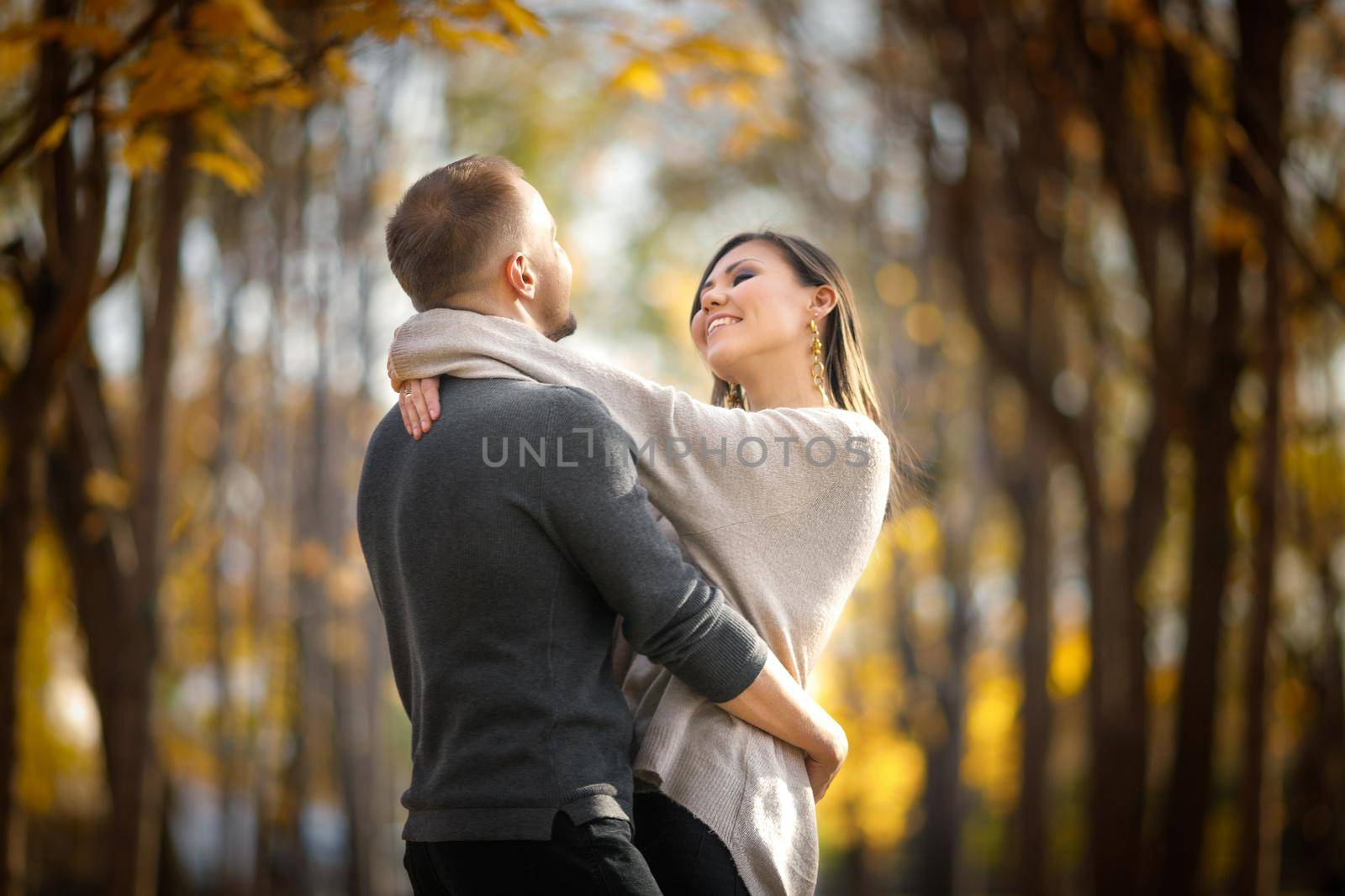 Gentle sunny hugs of a guy and a girl in love at sunset in an autumn outdoor.