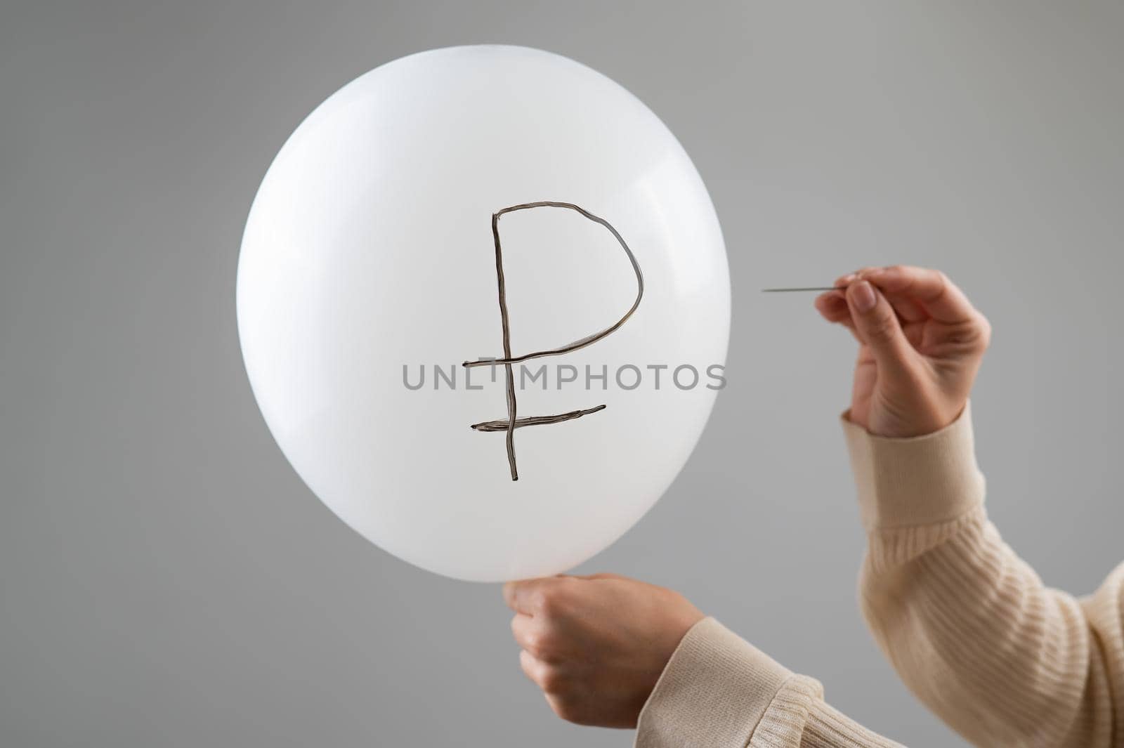 Caucasian woman pops a balloon with a ruble inscription with a needle. by mrwed54