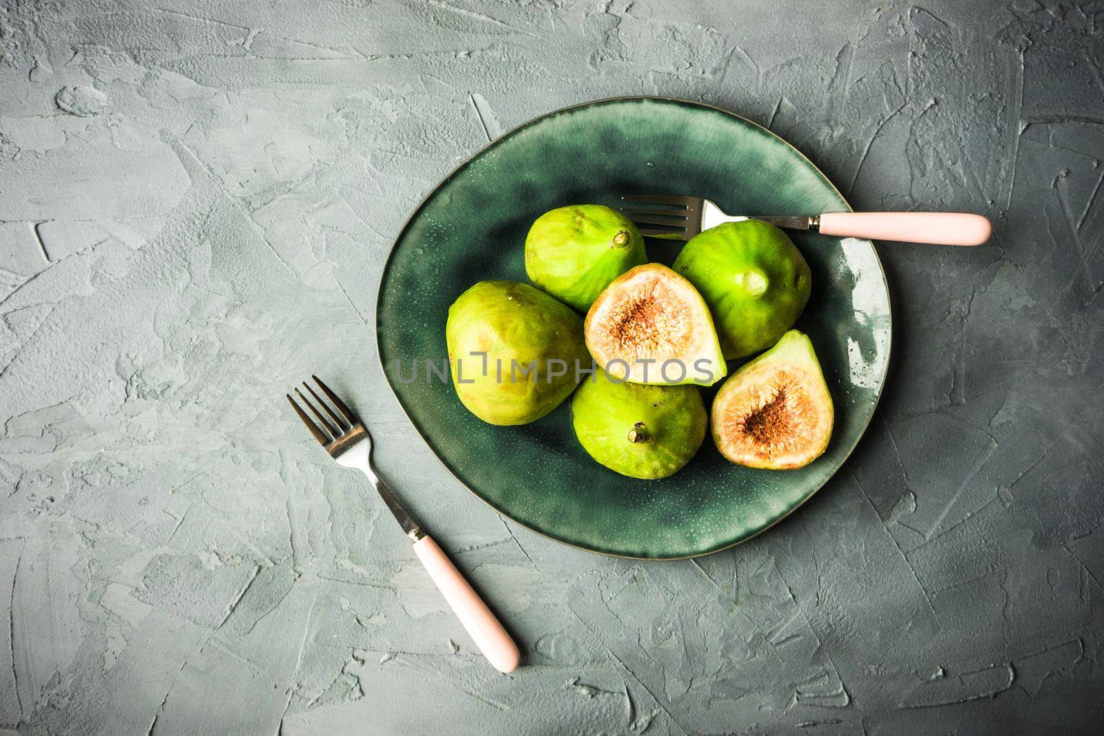 Organic fig tree fruits on the vintage plate on concrete background with copyspace