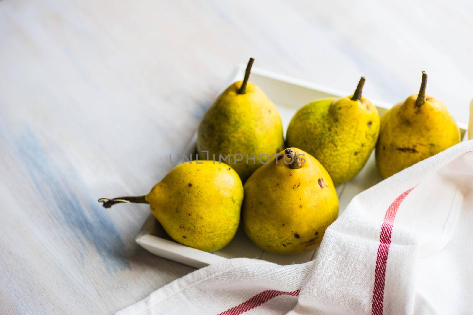 Organic pear fruits on the vintage plate on wooden background with copyspace