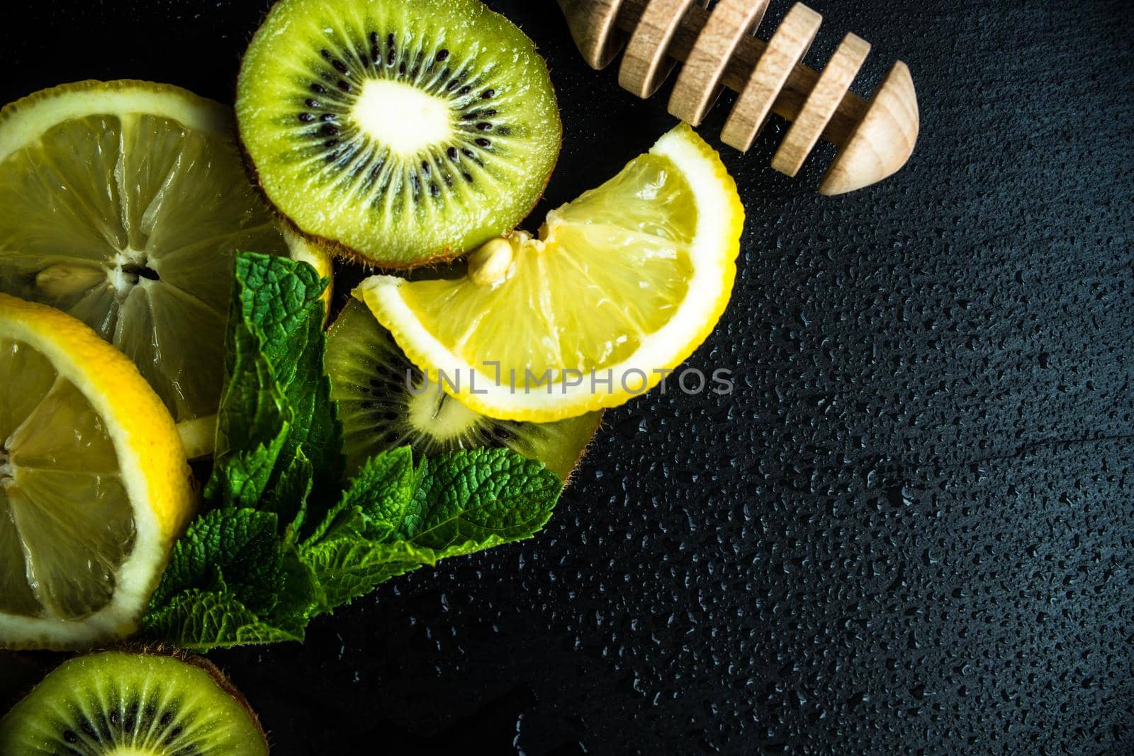 Flat lay with kiwi, lemon and mint on stone background with copyspace