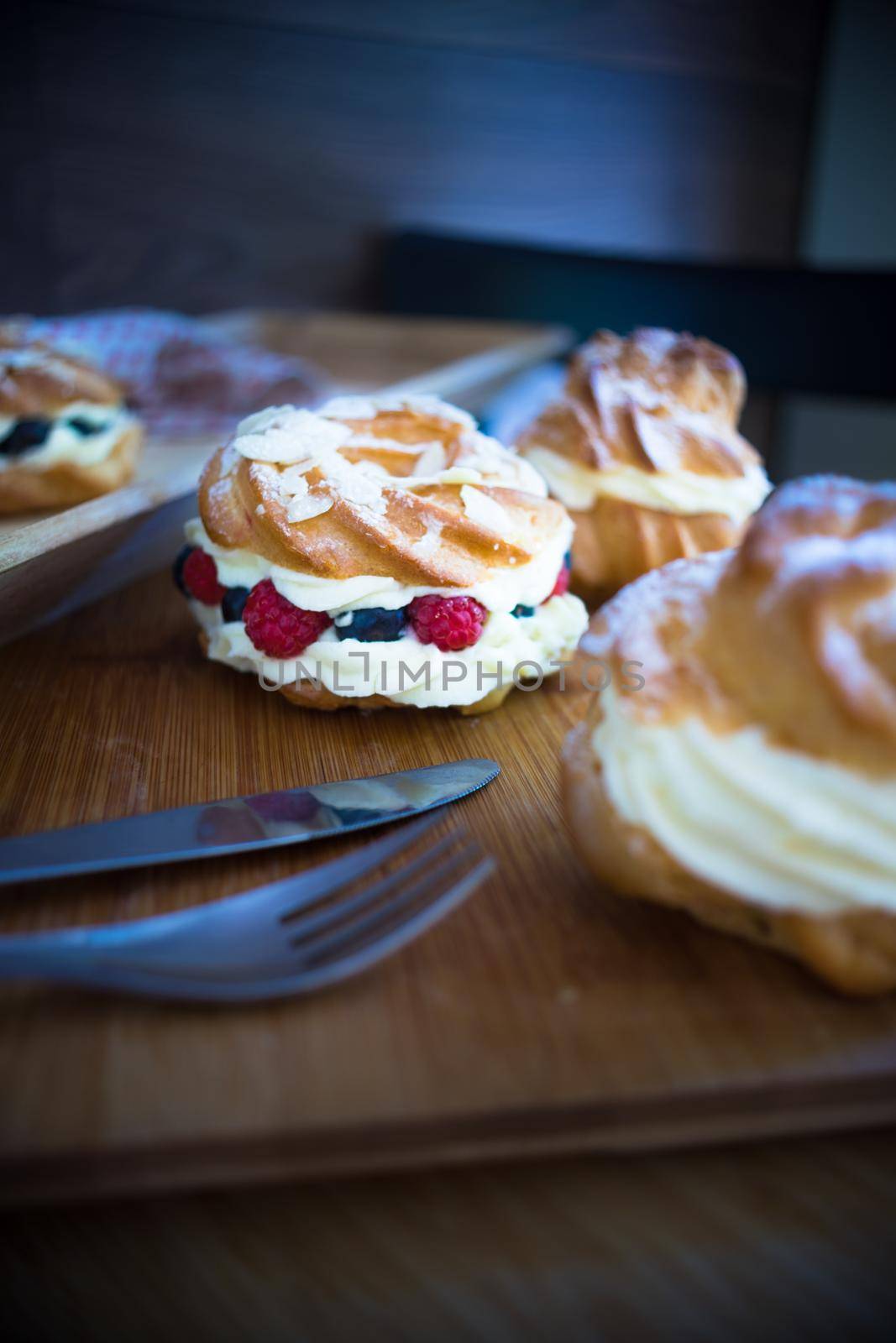 Dessert profitrole with vanila cream and ripe fresh berries like a strawberry, bilbery and rapsberry