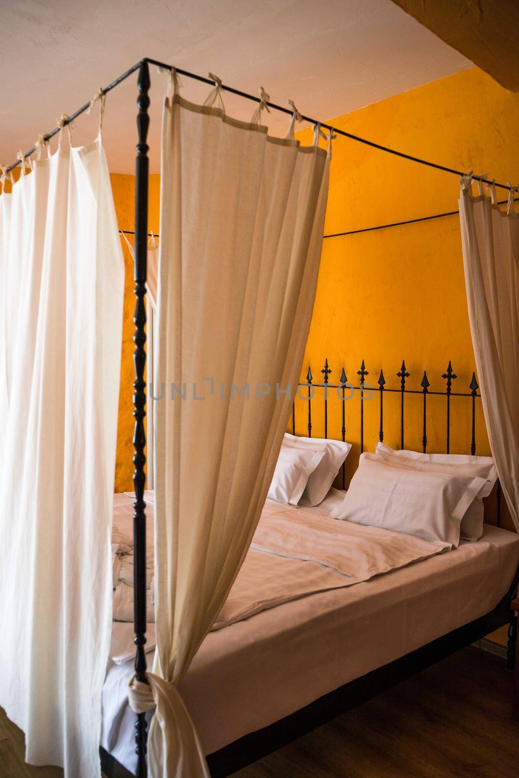 Old styled king size bed in orange bedroom