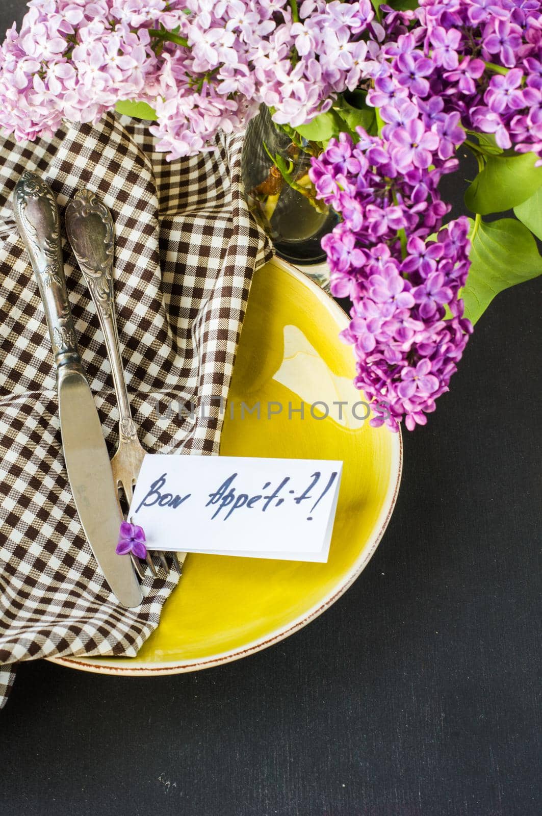 Spring table setting with bright lilac flowers on rustic background with copyspace