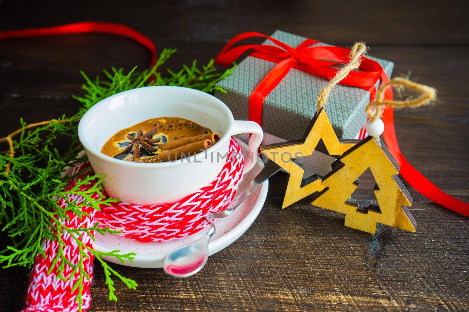 Mug of coffee with spices - cinnamon sticks and anise star with Christmas decor on dark wooden table with copyspace