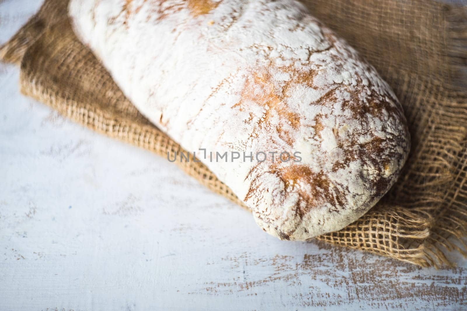 Fresh baked italian bread - ciabatta  on rustic table with napkin