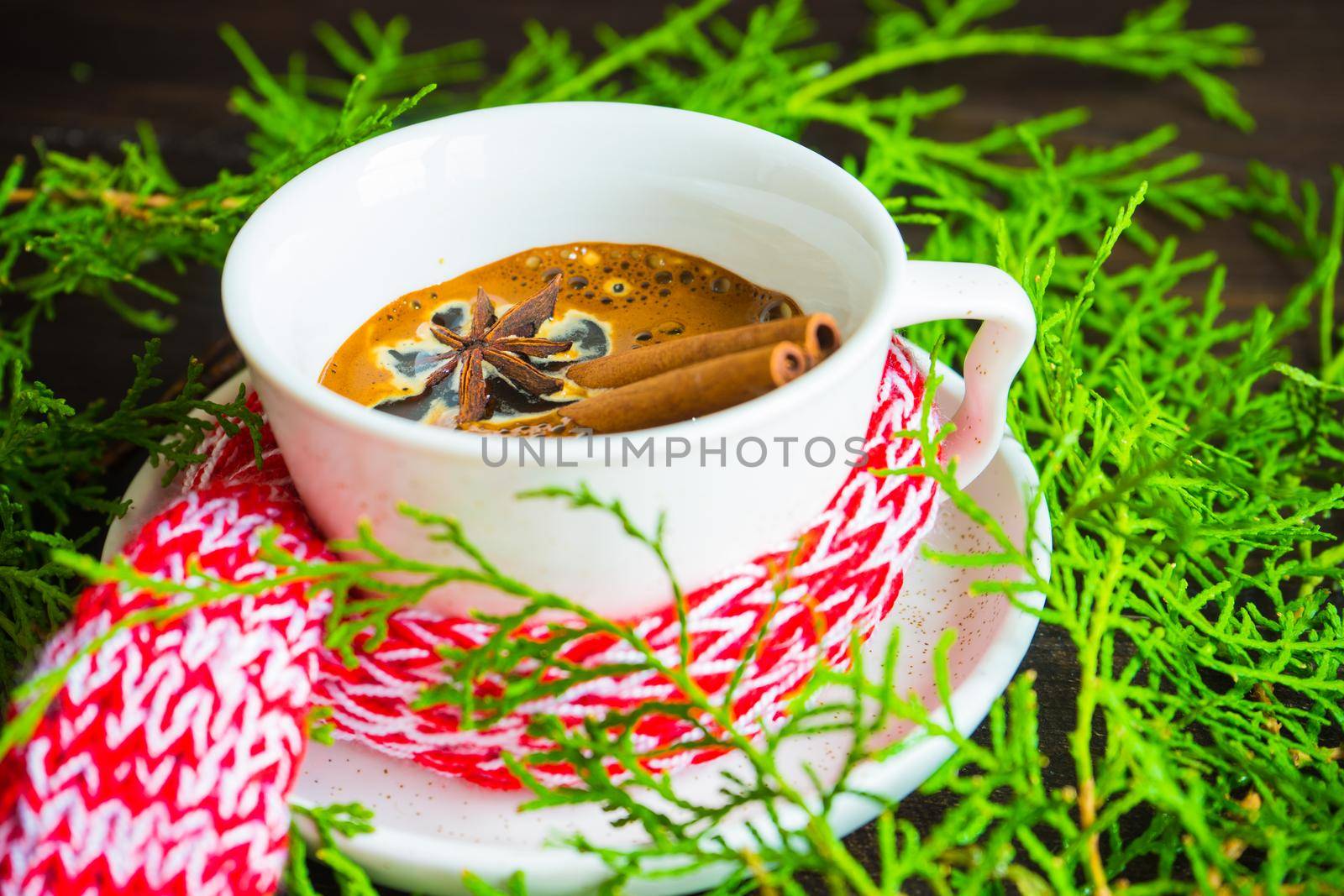 Mug of coffee with spices - cinnamon sticks and anise star with Christmas decor on dark wooden table with copyspace