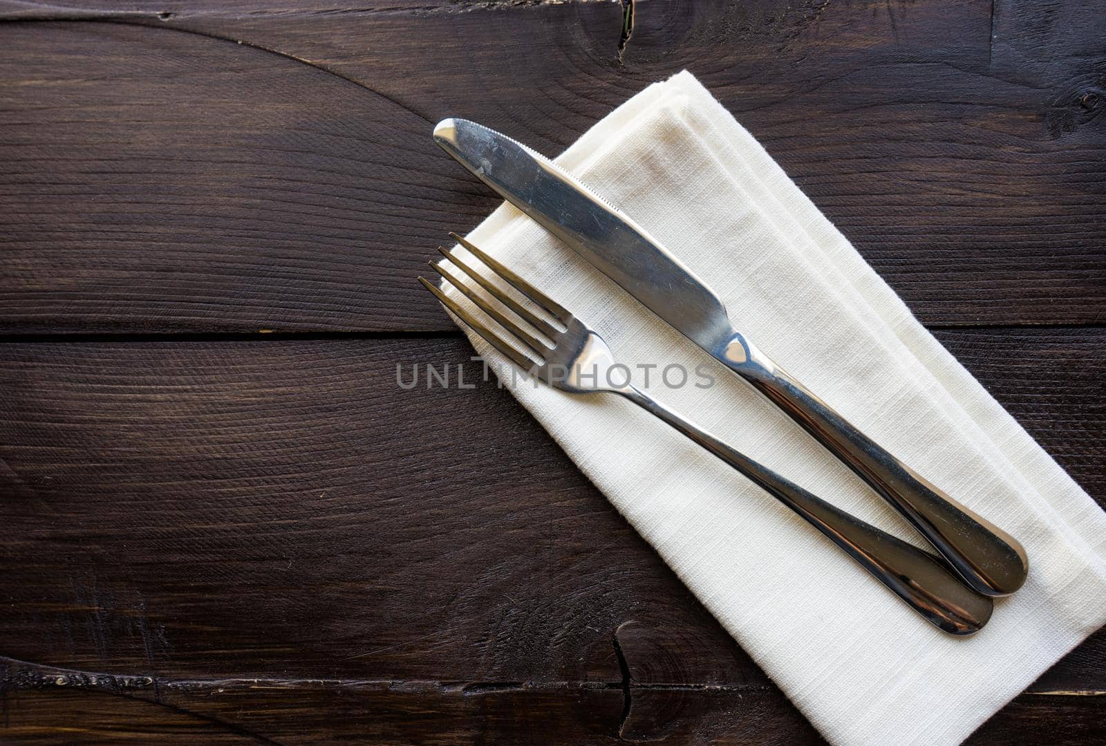 Rustic table setting with bright napkin nd silverware on dark wooden table