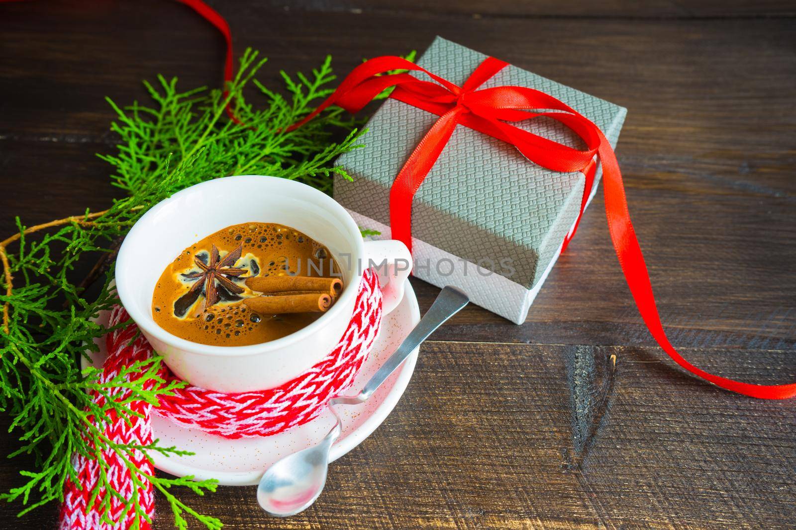 Mug of coffee with spices - cinnamon sticks and anise star with Christmas decor on dark wooden table with copyspace