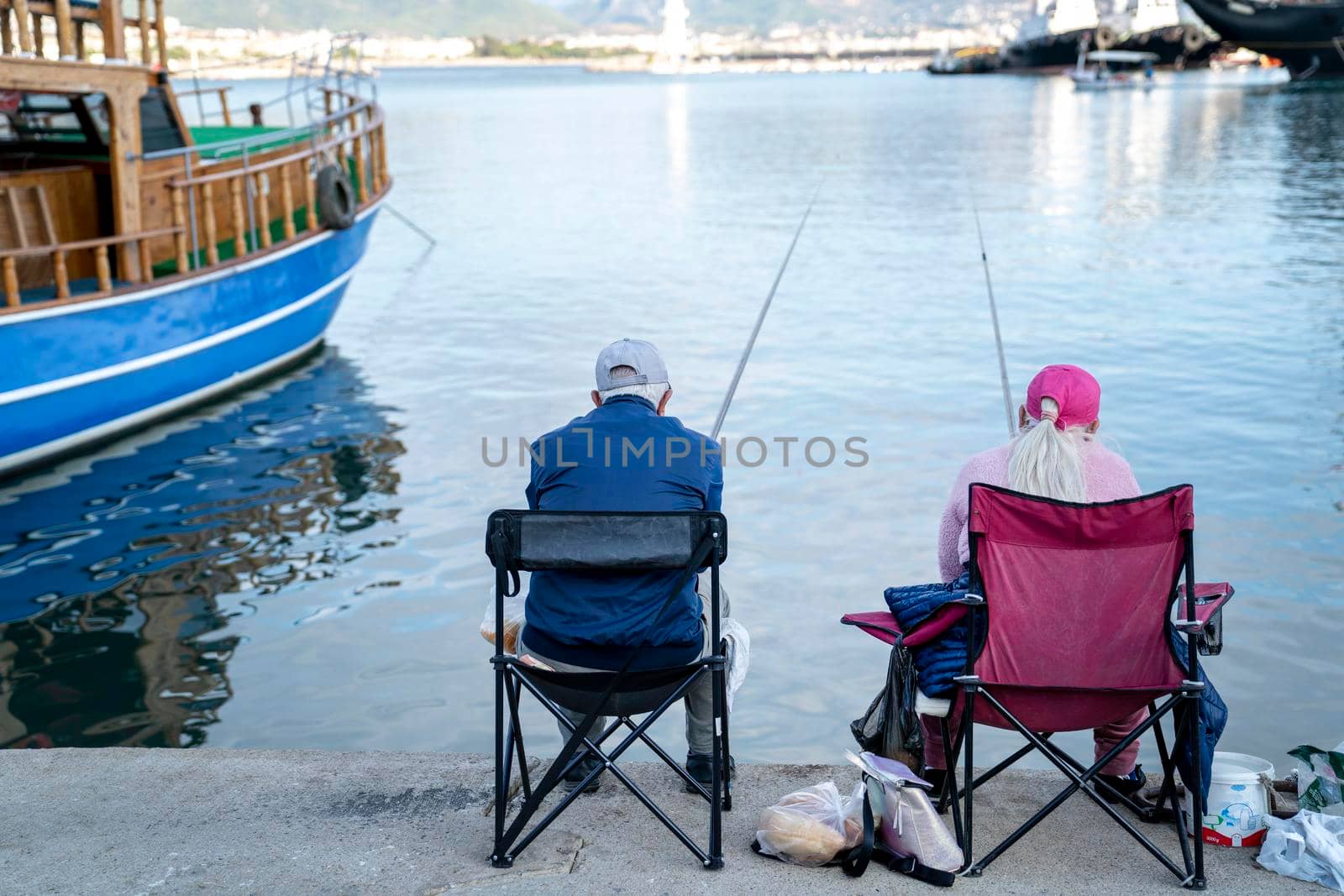 Turkey, Alanya - November 9, 2020: Elderly couple is fishing in the port of Alanya. Pleasant leisure and lifestyle of pensioners. 