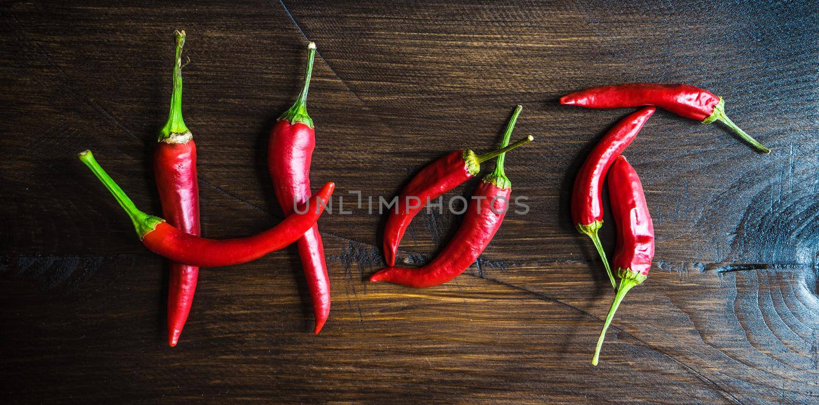 Organic chilli peppers on a pan on dark wooden background with copyspace