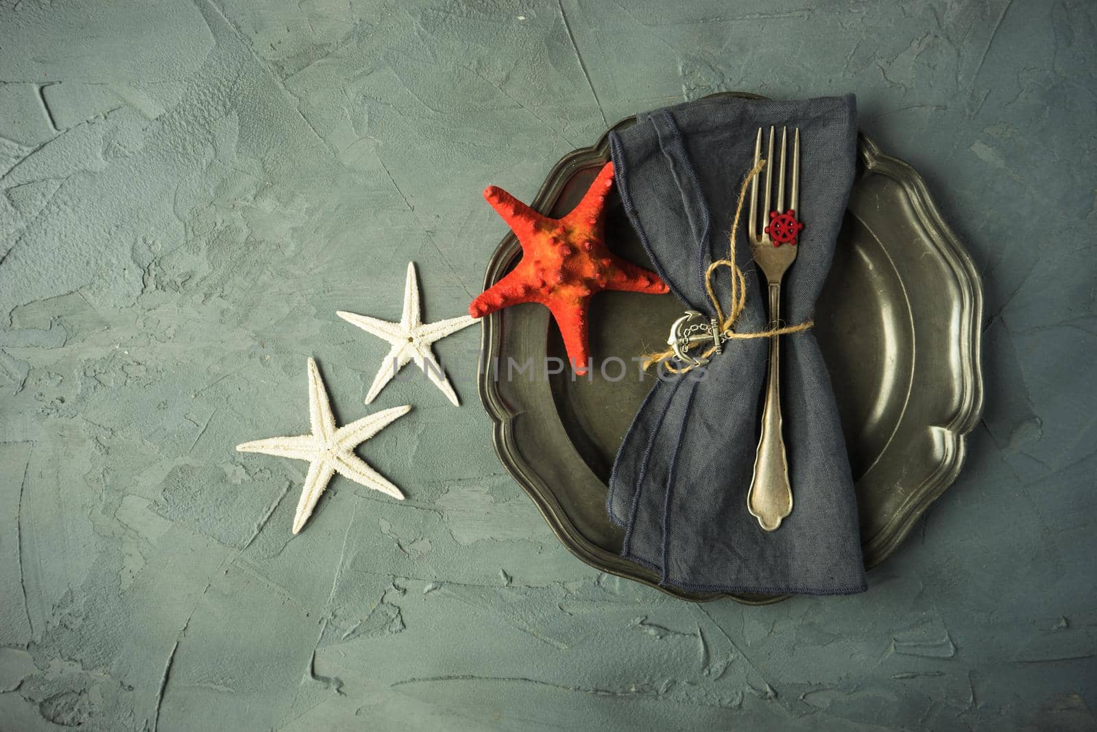 Summer vacation marine table setting with rustic plates and silverware on wooden background with copyspace