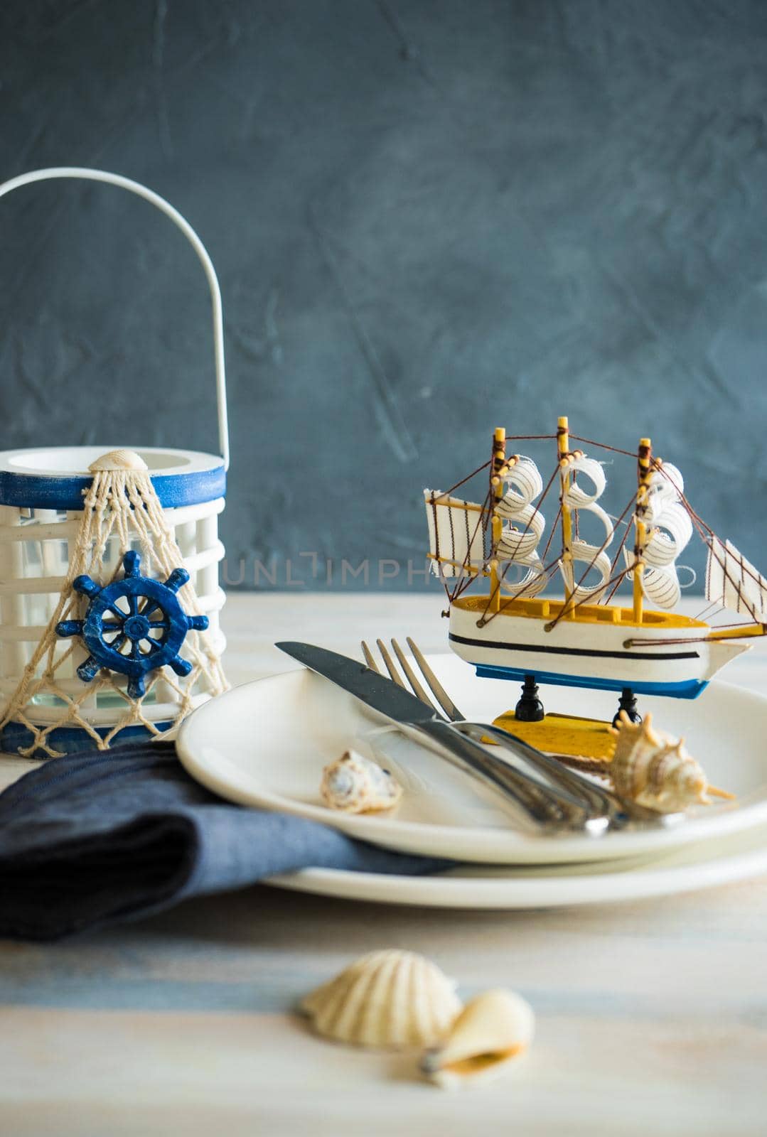 Summer vacation marine table setting with rustic plates and silverware on wooden background with copyspace