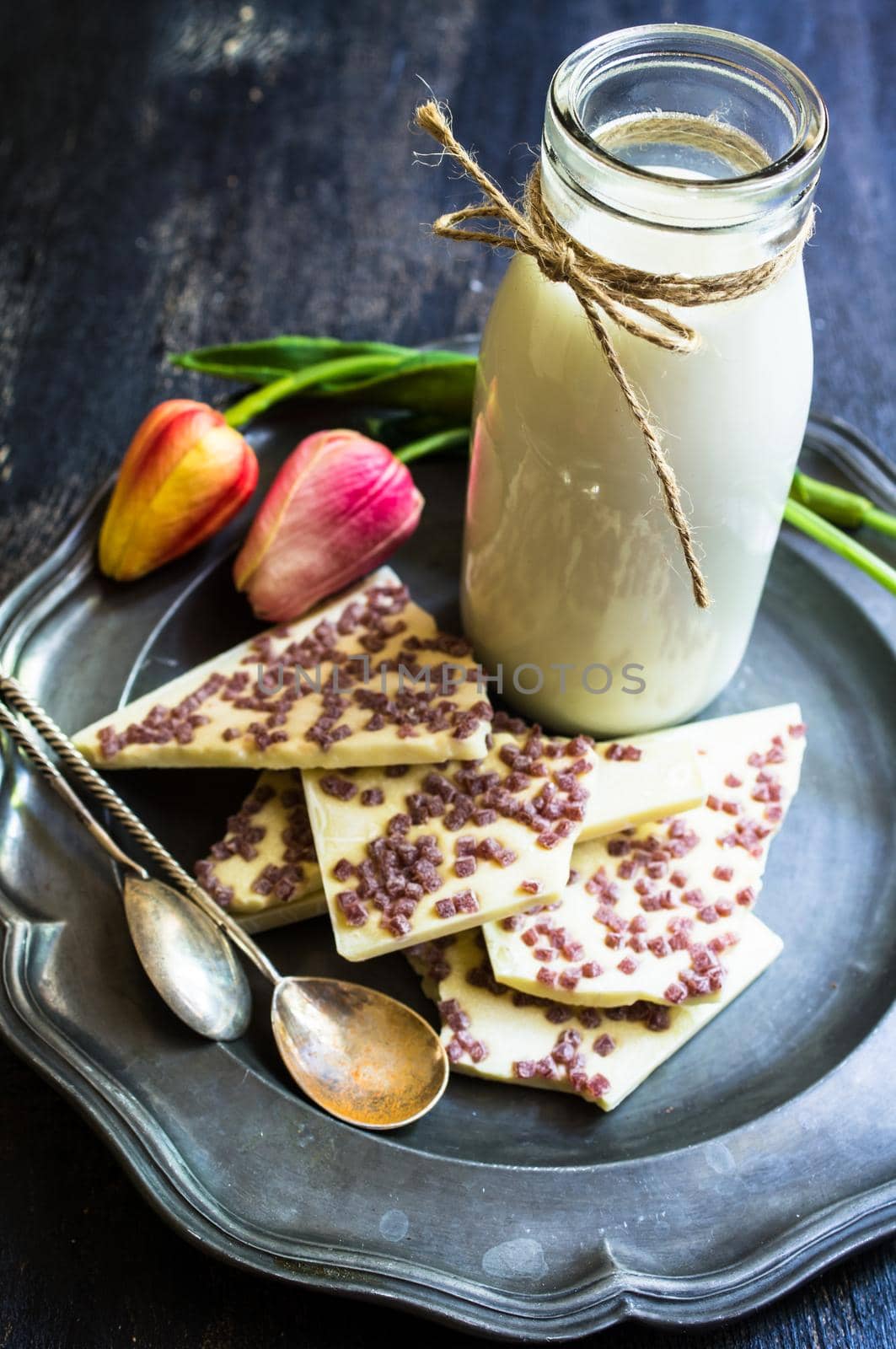 Vintage bottle of milk and white chocolate on rustic wooden table