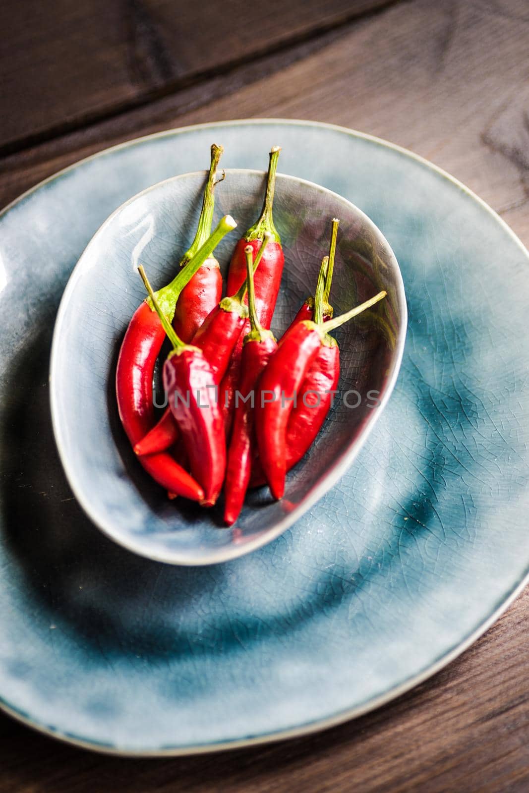 Organic chilli peppers on a pan on dark wooden background with copyspace