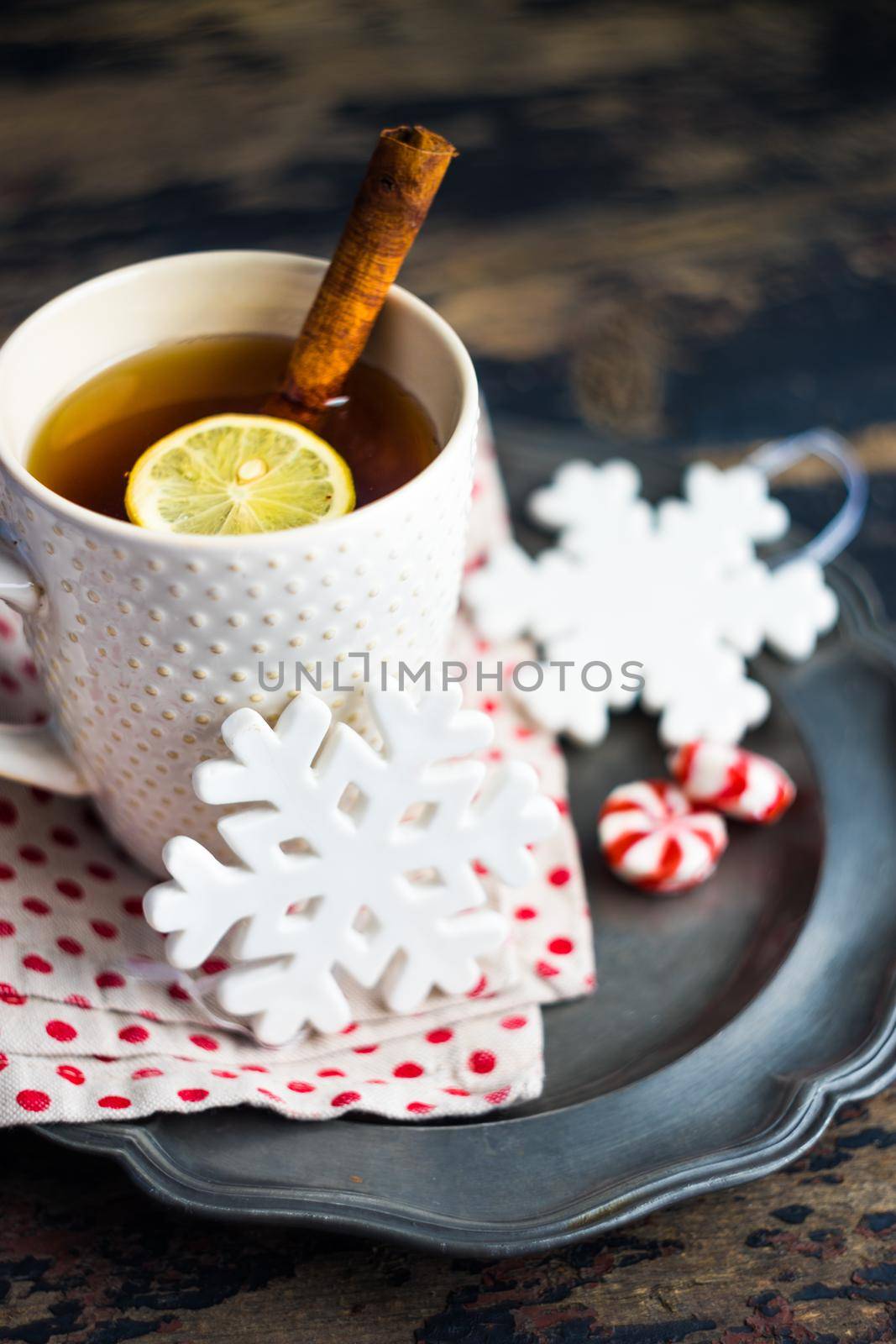 Cup of tea with lemon and cinnamon spice and Christmas decoration on rustic wooden table