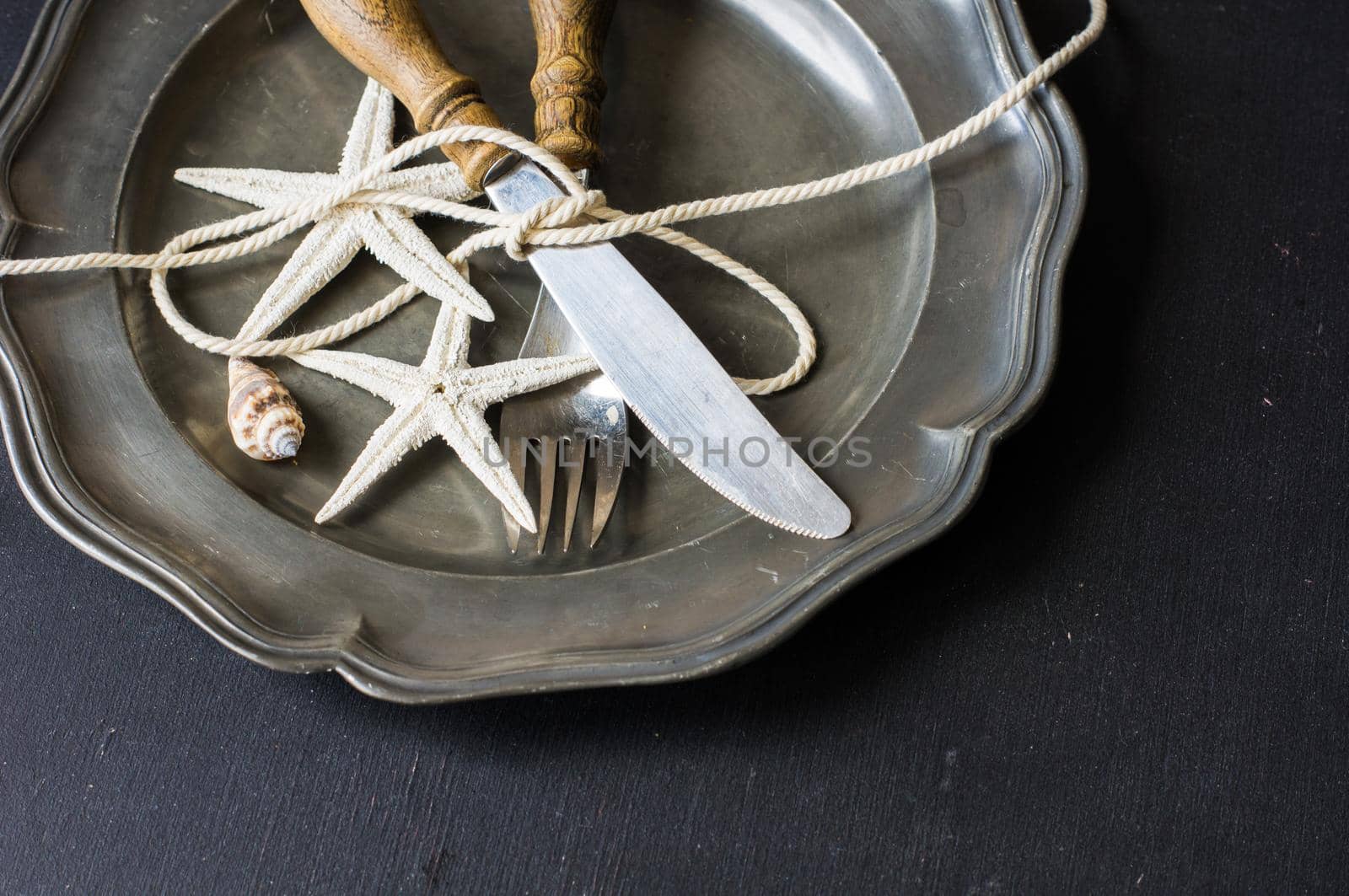 Summer vacation marine table setting with rustic plates and silverware on wooden background with copyspace