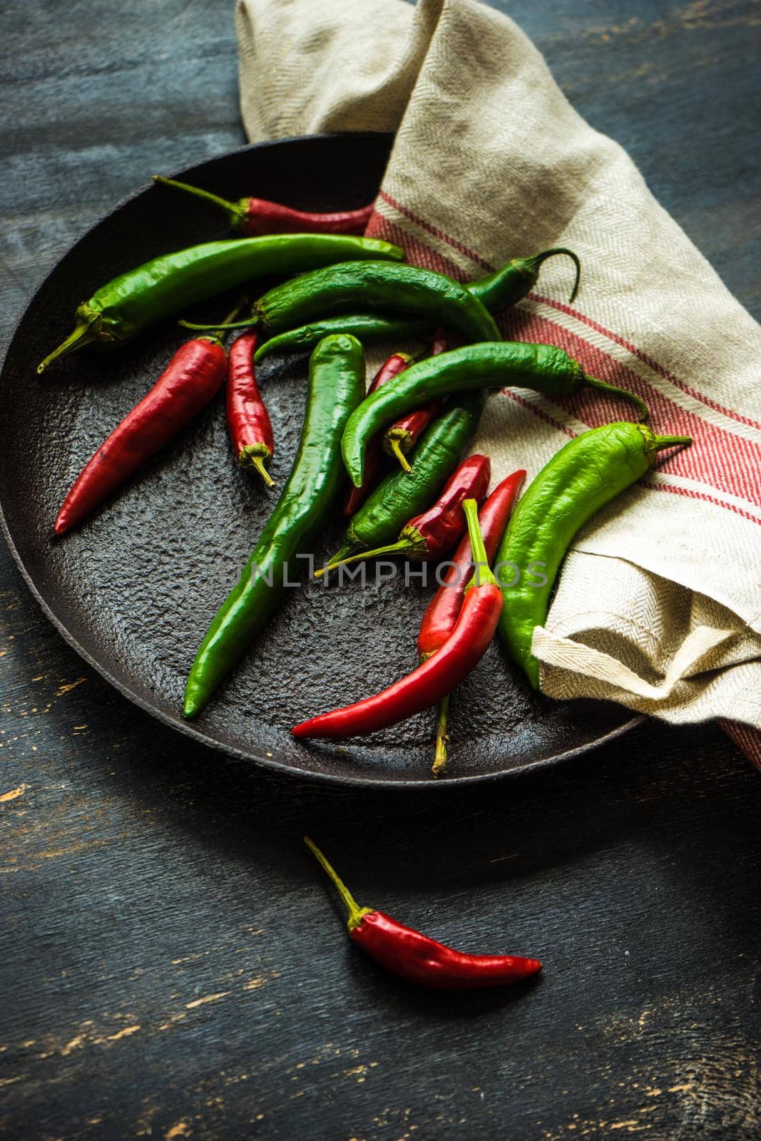 Organic chilli peppers on a pan on dark wooden background with copyspace