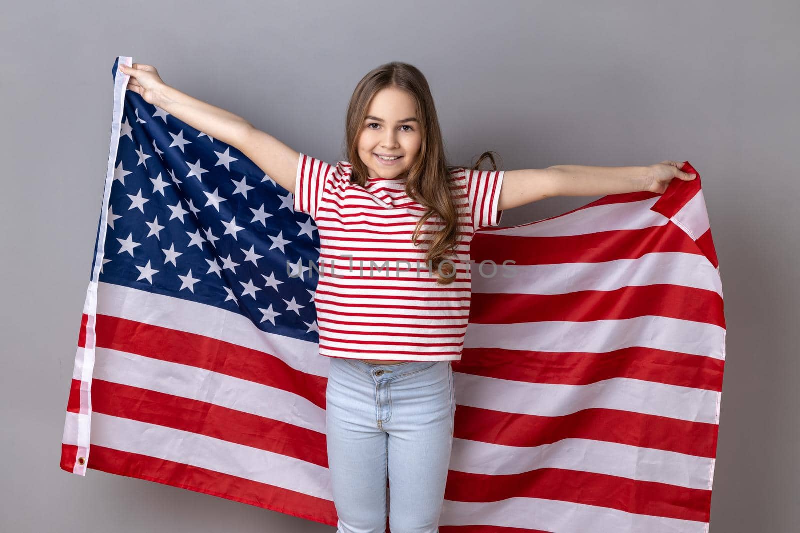 Little girl wearing holding huge american flag and yelling happily, celebrating national holiday. by Khosro1