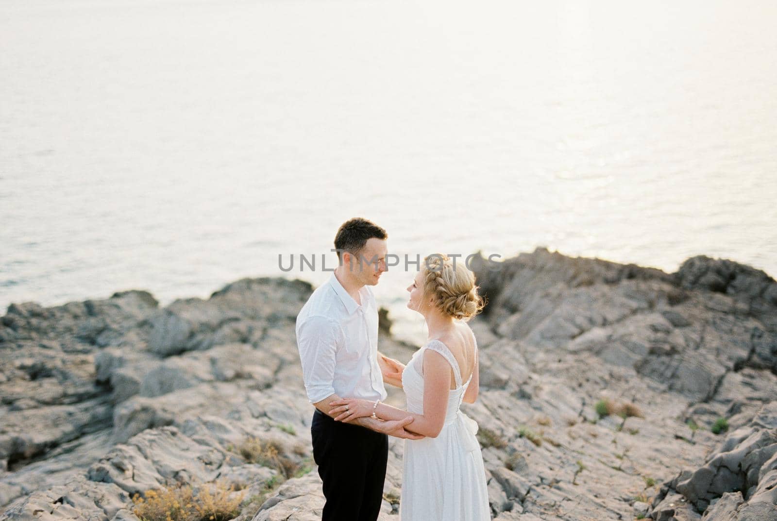 Bride and groom look into each other eyes, hugging forearms. High quality photo