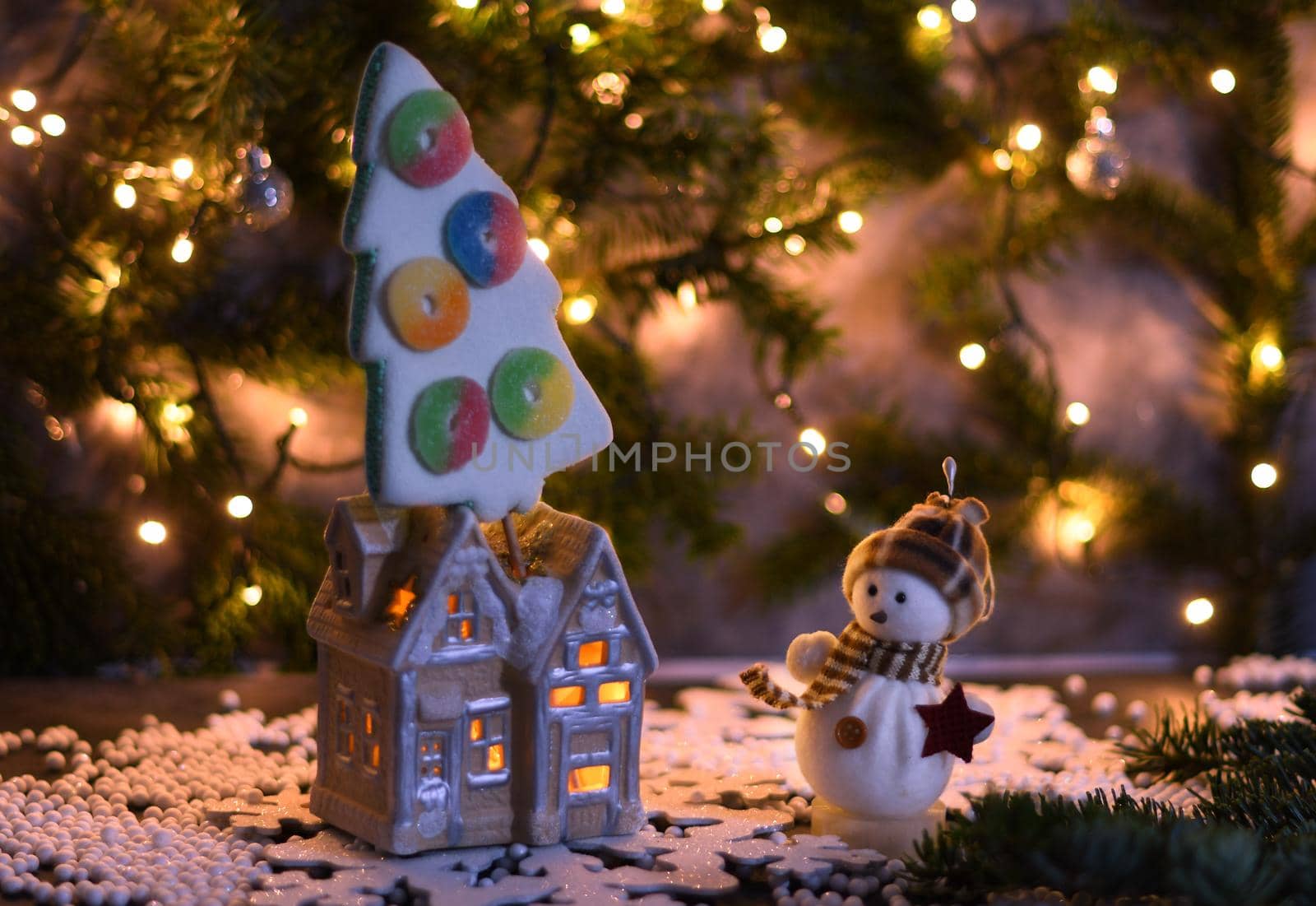 Christmas party in the toy village, a house with light in the windows and a marshmallow tree, sparkler and bokeh from a garland. High quality photo
