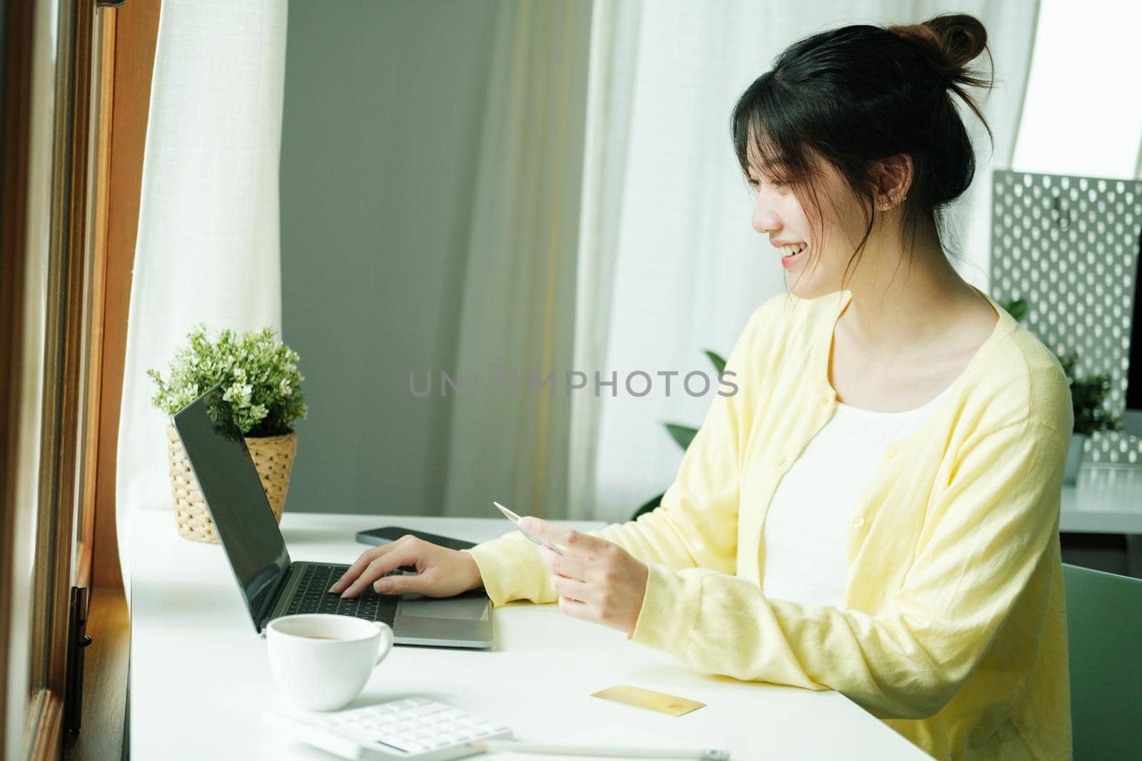 Close up asian woman using credit card for purchasing and shopping online on laptop computer.