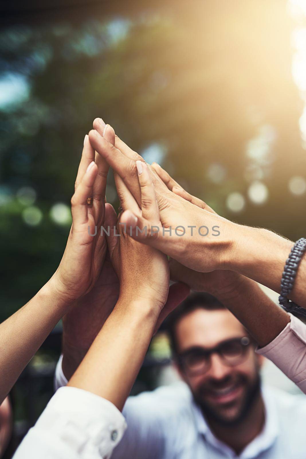 High five to our next big success. a group of colleagues high fiving outdoors. by YuriArcurs