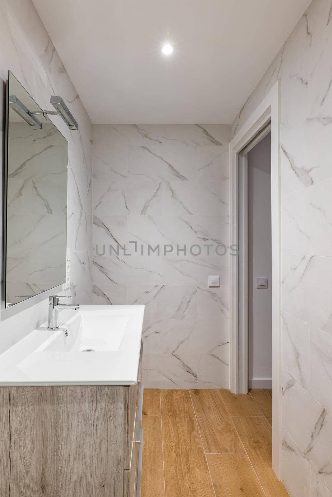 Bathroom with white tiles, mirror, ceramic sink under a wardrobe in a modern house or office. by apavlin