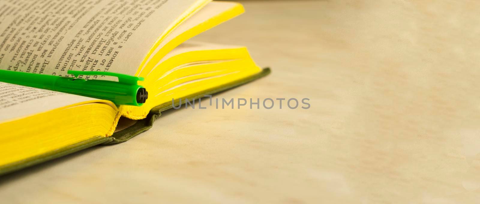 A green pen on an open book.The concept of education.Banner,copyspace